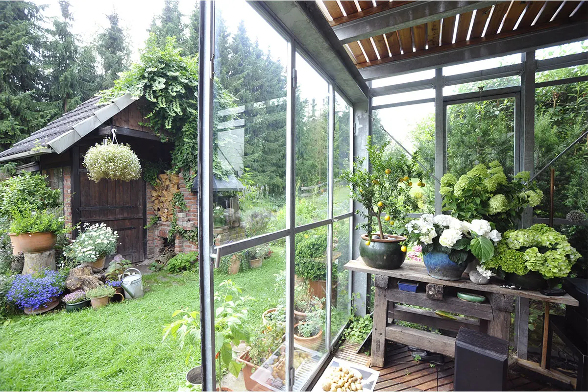 Wintergarten mit Sicht auf ein Gartenhaus Foto: AdobeStock_Klaus Rose