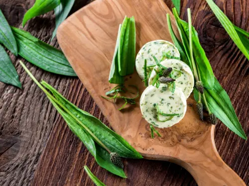 Kräuterbutter mit Spitzwegerich auf einem Holztablett
