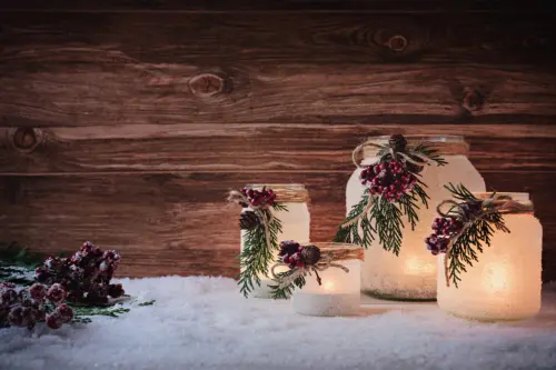 Windlicht basteln und zu Weihnachten mit Sprühschnee und Koniferengrün verzieren [Foto: AdobeStock_Emmi]