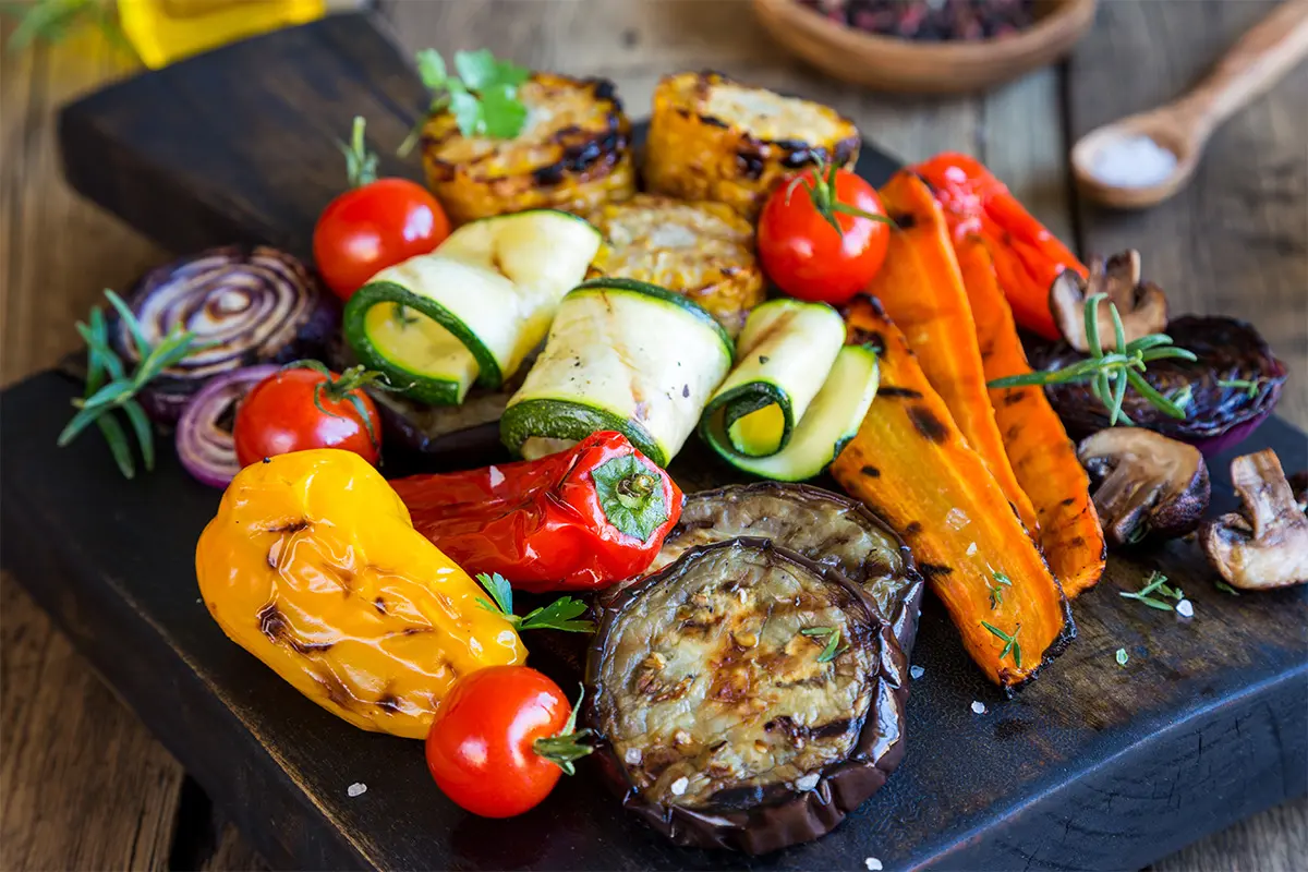 Grillgemüse auf einer Servierplatte. Paprika, Zucchini und Aubergine liegen hübsch angeordnet nebeneinander auf einer schwarzen Platte. [Foto: AdobeStock_juefraphoto]
