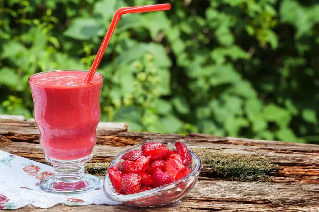Smoothie mit frischen Erdbeeren auf Gartentisch [Foto: AdobeStock_Fotoknips]