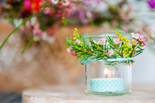 Windlicht mit Blumen auf einem Tisch [Foto: AdobeStock_Bevisphoto]