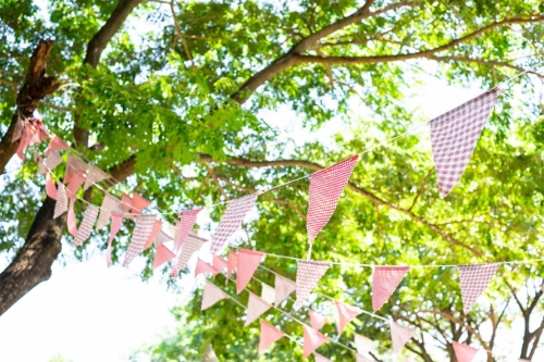 Girlande auf einer Gartenparty in den Ästen eines Baumes [Foto: AdobeStock_Patcharida]