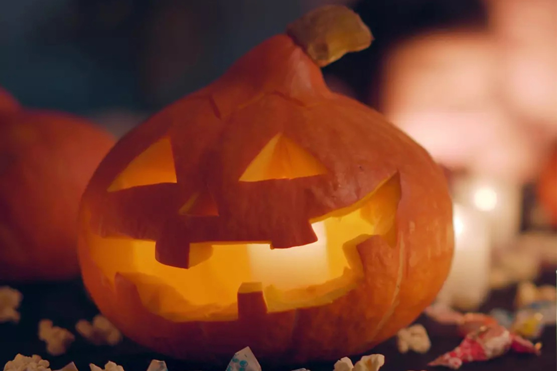 Nahaufnahme eines geschnitzten Halloweenkürbis mit entzündetem Teelicht