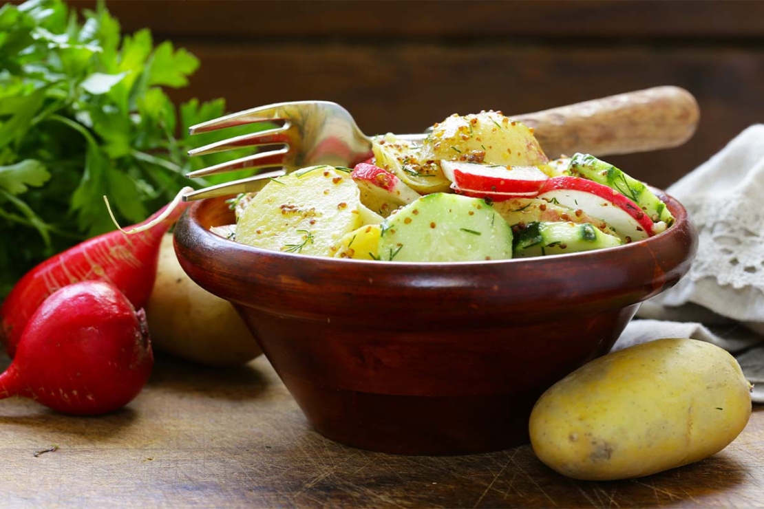 Schneller Kartoffelsalat mit Radieschen, Senf und Gurke in einer Schale [Foto: AdobeStock_Olga Kriger]