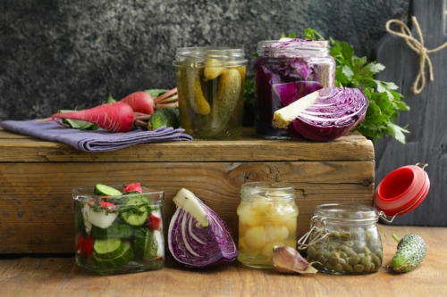 Frisches und fermentiertes Gemüse auf einer Holzbank arrangiert