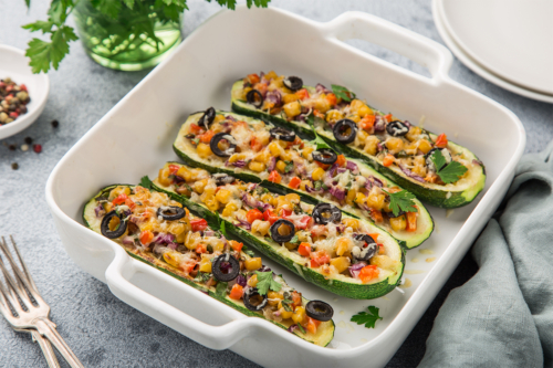 Mit Gemüse und Oliven gefüllte und überbackene Zucchini in einer Auflaufform