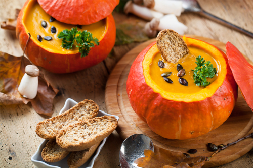 Kürbissuppe in eigener Schale auf einem Tisch mit krossem Brot [Foto: AdobeStock_Karepa]