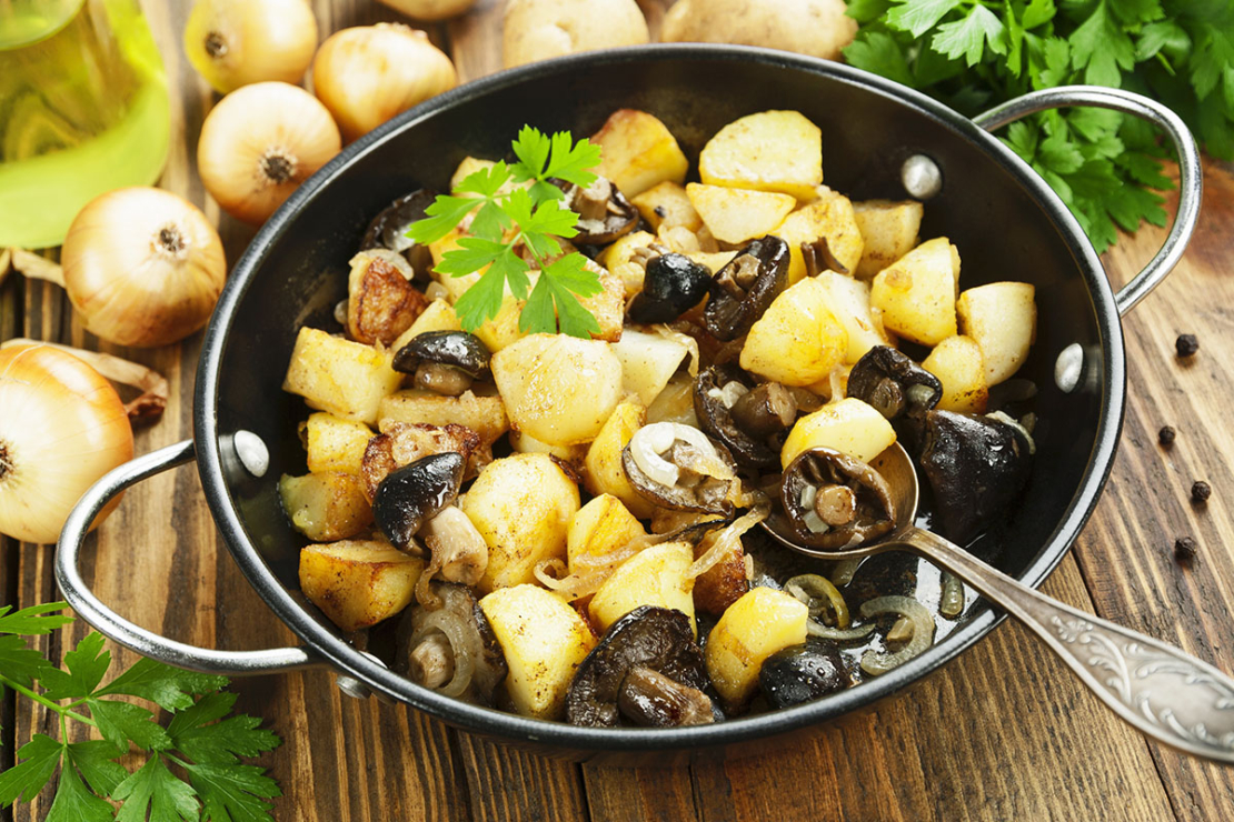Pilzpfanne mit Kartoffeln und Petersilie auf Holzbrettchen Foto: AdobeStock_minadezhda