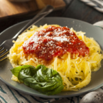 Spaghettikürbis als Nudeln angerichtet mit Tomatensauce und Käse [Foto: AdobeStock_Brent Hofacker]