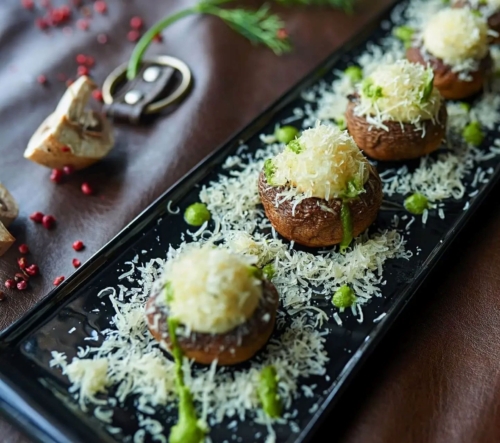 Zu sehen ist ein Teller, der mit gefüllten Champignons gefüllt ist.