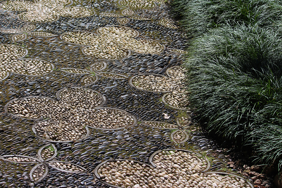 Steinbesetzter Weg mit Mosaikmuster neben Schlangebart. Foto: AdobeStock_Rose