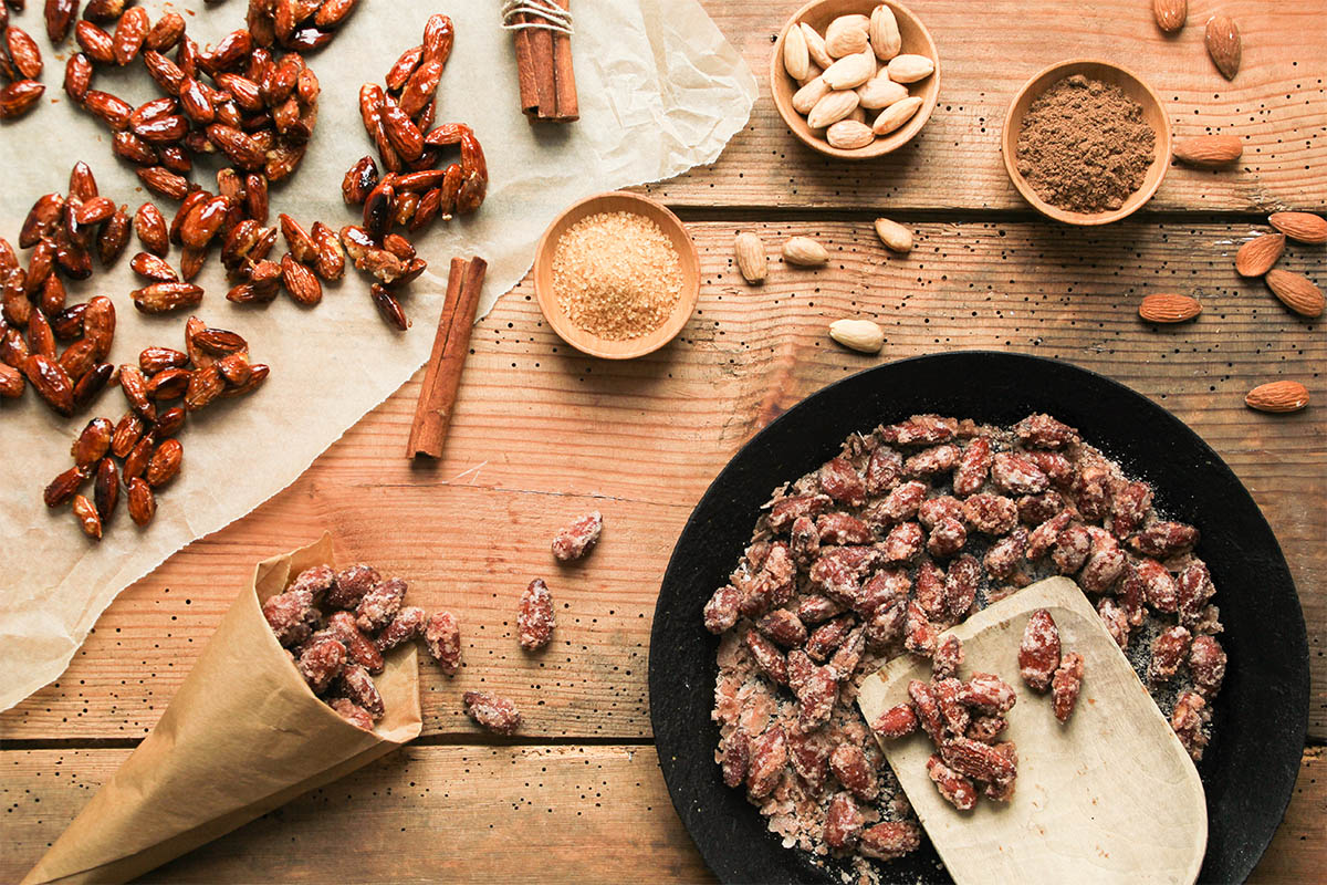 gebrannte Mandeln in gusseiserner Pfanne, in Tüte und auf Backpapier Foto: AdobeStock__Eflstudioart