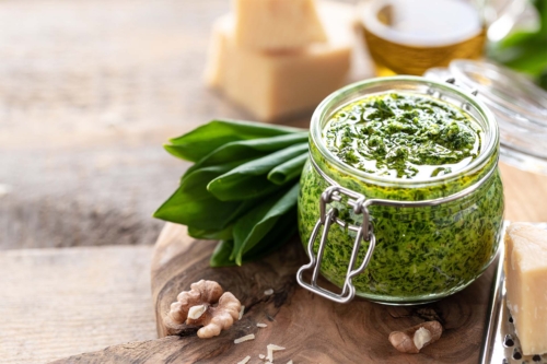 Baerlauchpesto im geoeffneten Weckglas, garniert mit frischen Baerlauchblaettern [Foto: AdobeStock_Карина Клачук]