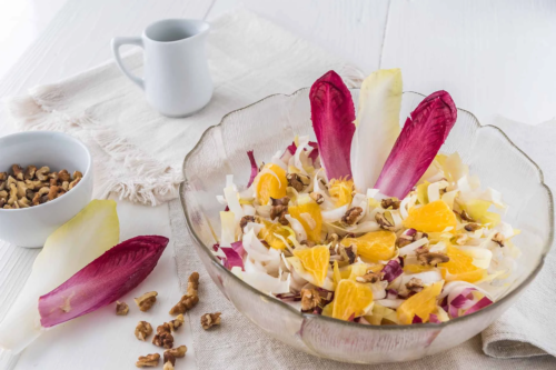 Chicorée Salat mit einem leckeren Joghut-Curry-Dressing und Orangenfilets in einer Glasschüssel [Foto: AdobeStock_Daniela-Baumann]