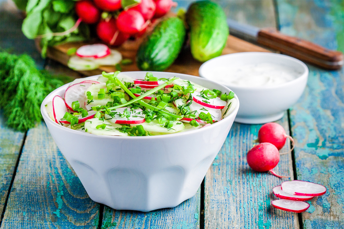 Radieschensalat mit Gurken in Schale auf hellblauem Holztisch Foto: AdobeStock_Nblxer