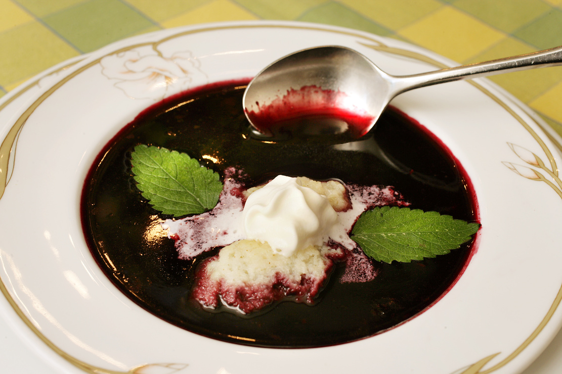 Holundersuppe mit Grießklößchen, Schlagsahne und zwei Blättern Zitronenmelisse. Foto: AdobeStock_Jörg Lantelme