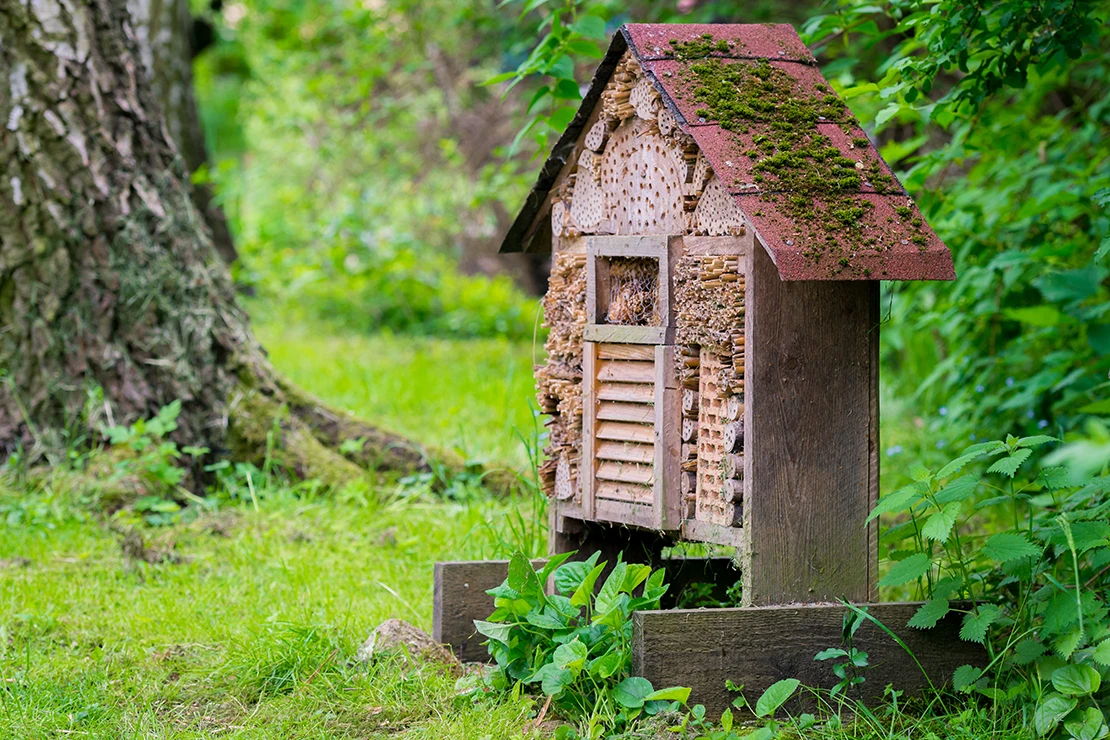 Ein Insektenhotel mit spitzem Dach in einem Garten. Foto: AdobeStock_mirkograul