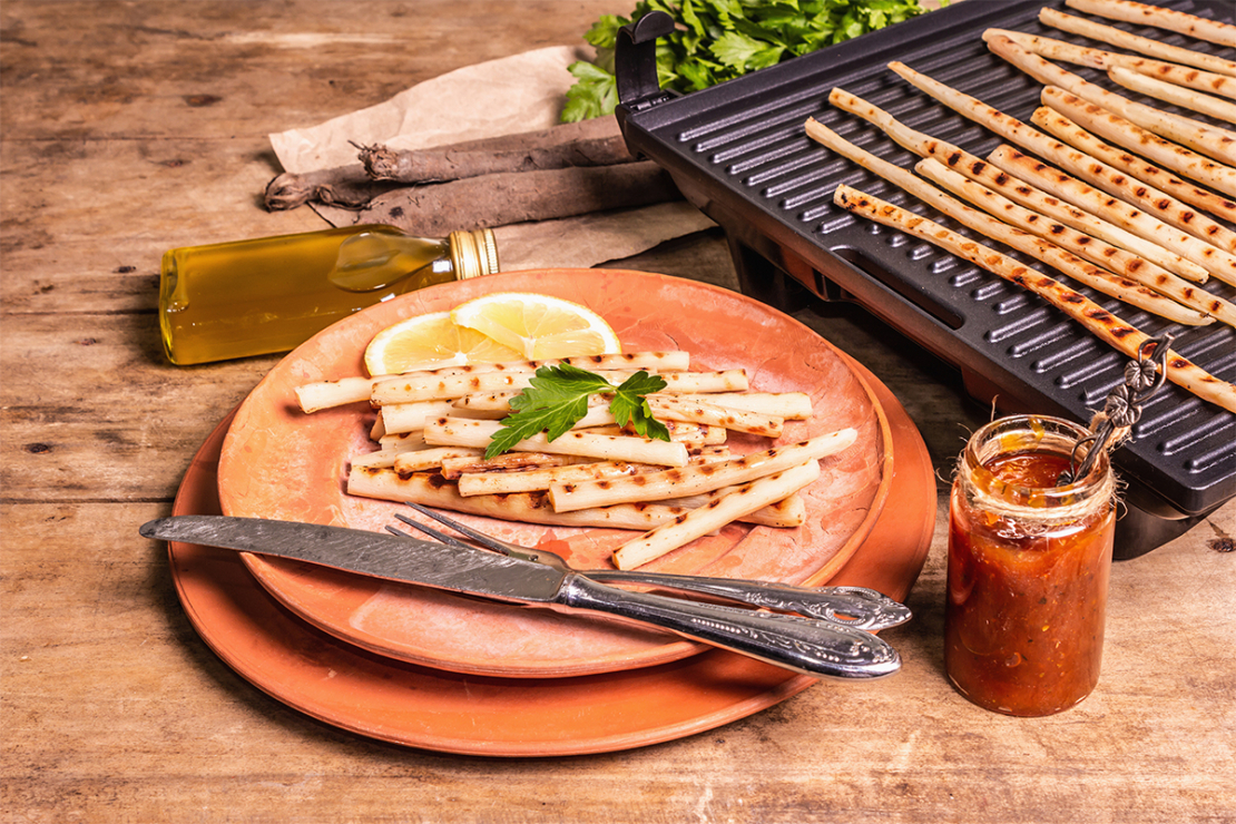 Schwarzwurzeln Rezept von einem Kontaktgrill mit dem fertigen Gericht auf einem Teller daneben[Foto: AdobeStock_FuzullHanum]