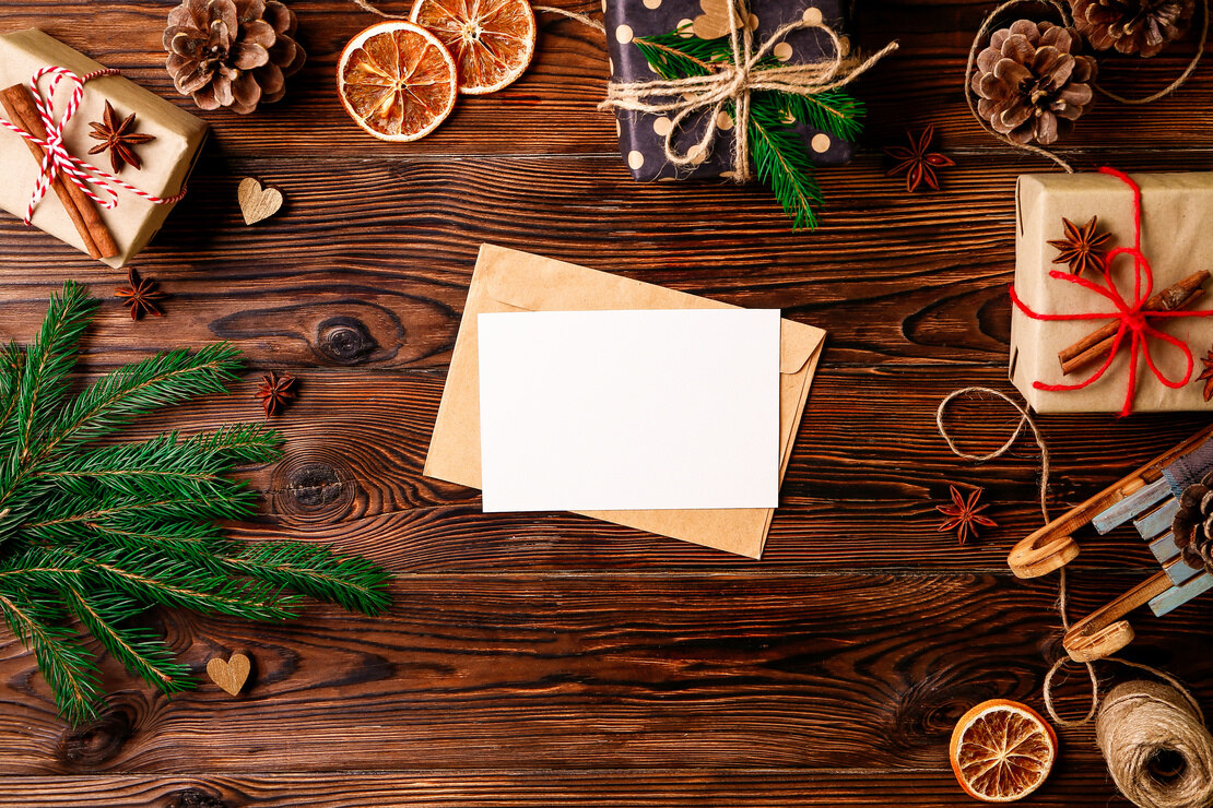 Nachhaltige Weihnachtsgeschenke: Briefpapier inmitten weihnachtlicher Dekoration auf einem Holztisch. Foto: AdobeStock_Evrymmnt