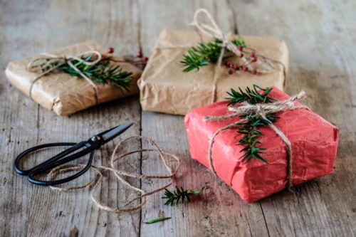 Nachhaltig verpackte Weihnachtsgeschenke auf einem Holzboden.