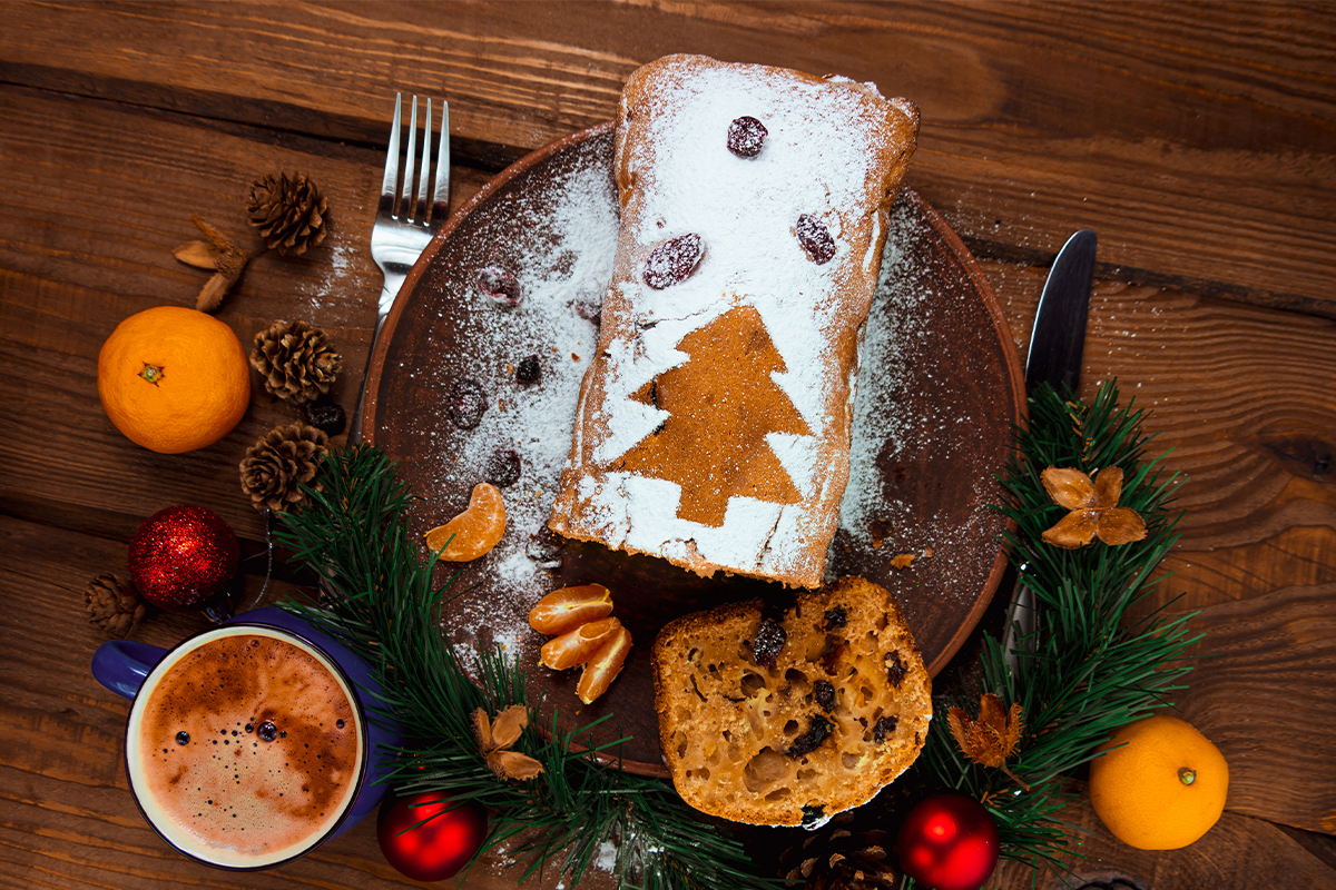 weihnachtlicher Früchtekuchen mit Orangenschalen auf einem Holztisch [Foto: AdobeStock_KawaiiS]