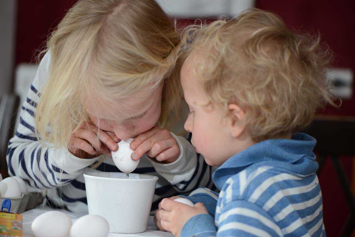 Basteln mit Eierschalen: Kinder beim Eier ausblasen [Foto: AdobeStock_Lunaundmo]