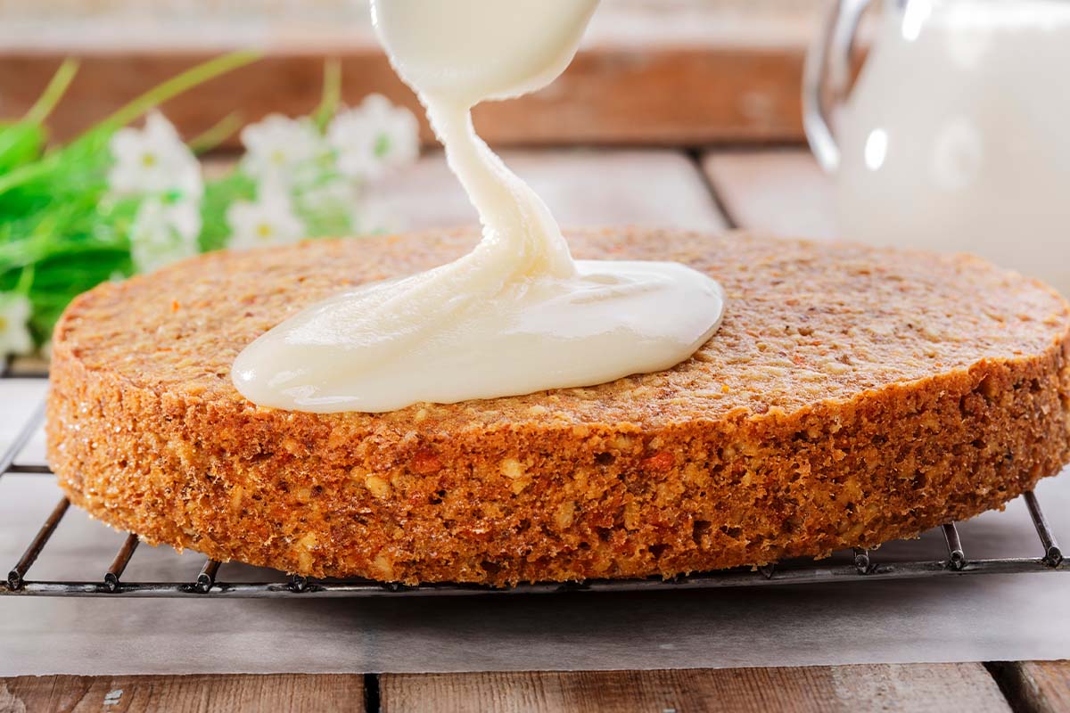 Rueblikuchen wird mit Frischkäse-Creme betraeufelt [Foto: AdobeStock_koss13]