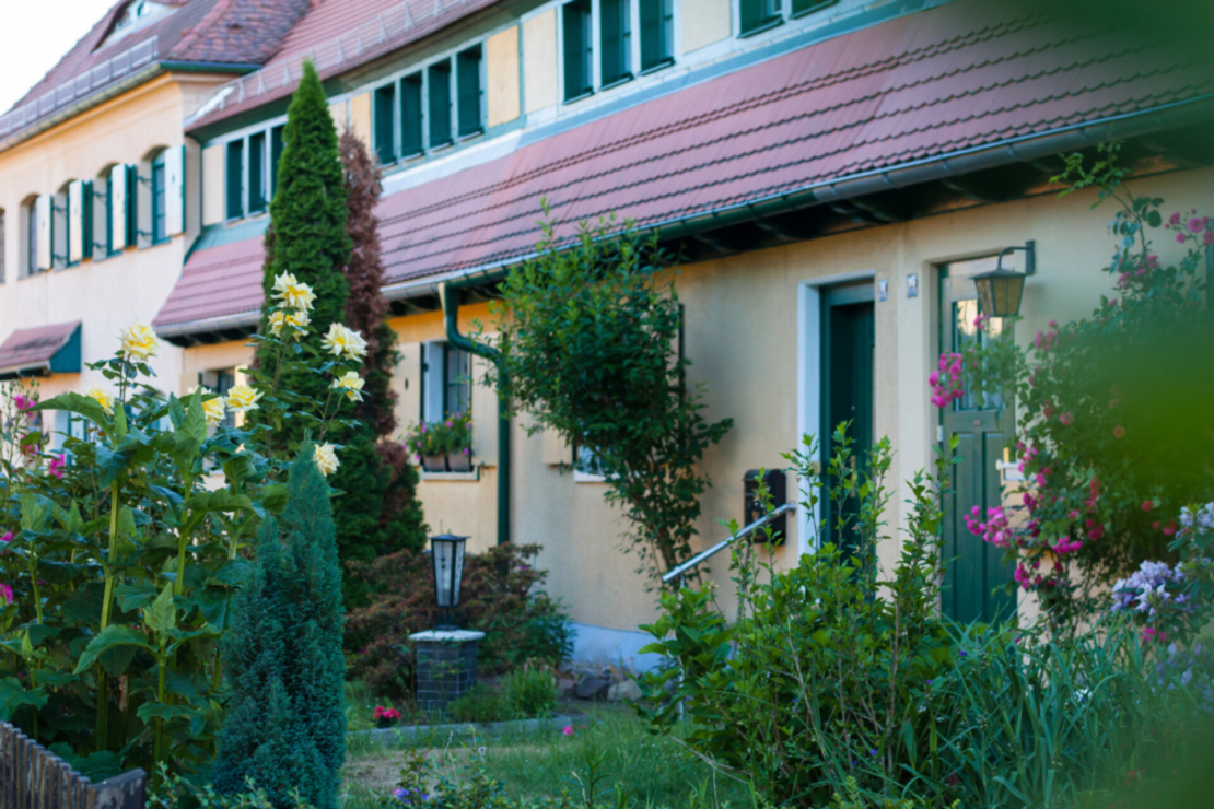 Gartenstadt: ein gelbes Haus in Dresden Hellerau. Vor dem Haus wachsen verschiedene Pflanzen. Foto: AdobeStock_ankenever