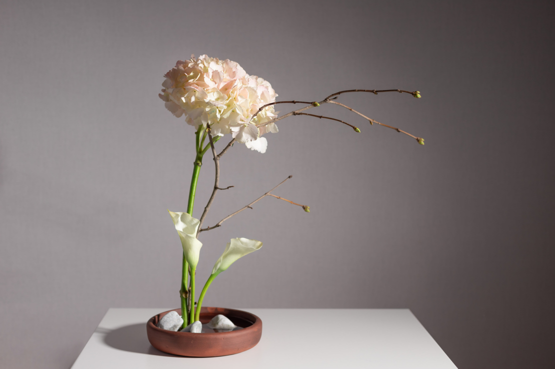Ikebana-Arrangement in brauner, flacher Schale. Foto: AdobeStock_Mila Naumova