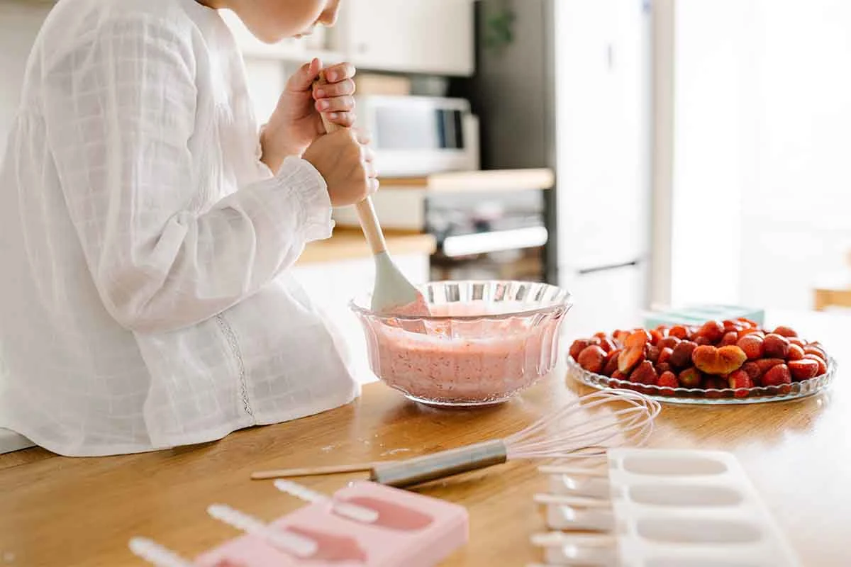 Hier wird Erdbeereis von einem Kind zubereitet. [Foto: AdobeStock_Sweetlaniko]