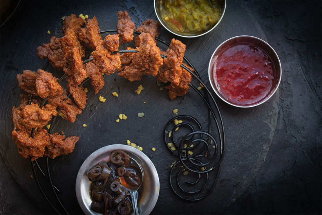 Grillfackeln aus Seitan auf einer Platte neben Saucen [Foto: AdobeStock_Adelina]