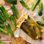 So können Sie Gewürzgurken selber machen. Hier sehen Sie ein Einmachglas mit Gurken und viele kleine Gurken drumherum. [Foto: Adobestock-cherkasova-alie]