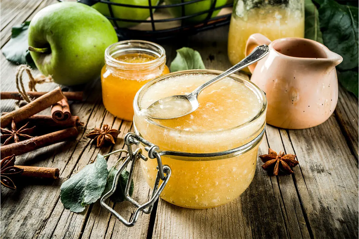 Apfelmarmelade selber machen – hier in einem Glas auf einem Löffel [Foto: AdobeStock_ricka_kinamoto]