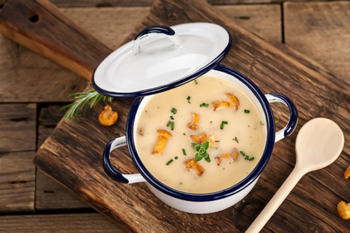 Pilzcremesuppe steht in einem Topf auf einem Holztisch [Foto: AdobeStock_Marek-Gottschalk]