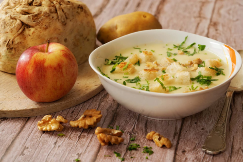 Selleriesuppe neben Aepfeln und Sellerieknolle auf einem Esstisch [Foto: AdobeStock_Babsi_w]