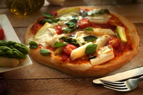 Spargelpizza mit Tomaten auf Holztisch