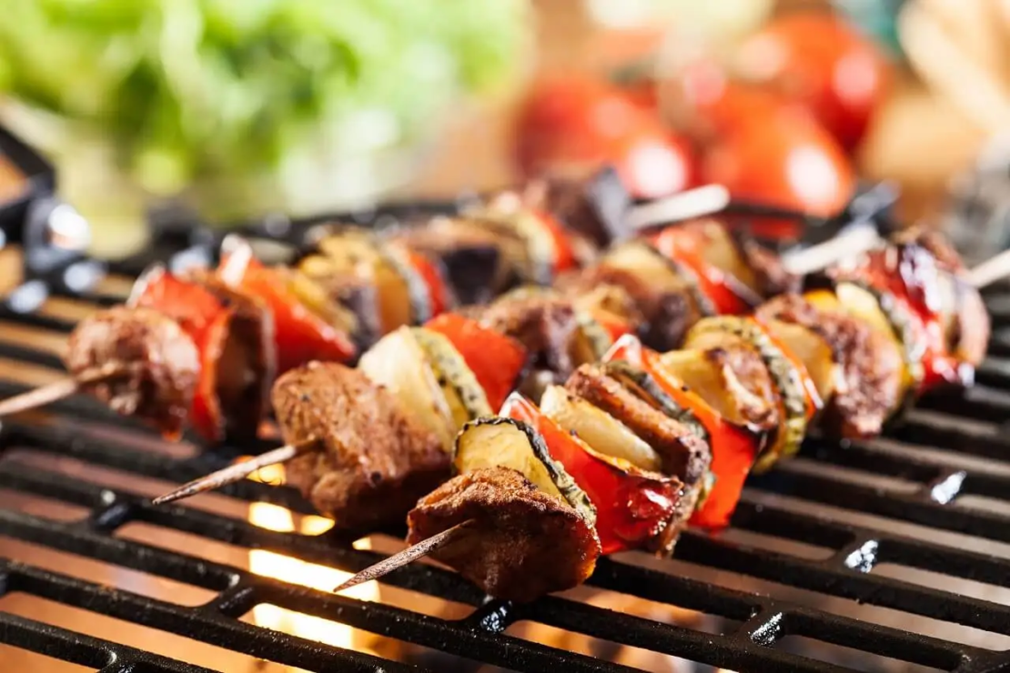 Drei Grillspieße auf dem Grill mit Gemüse und Fleisch