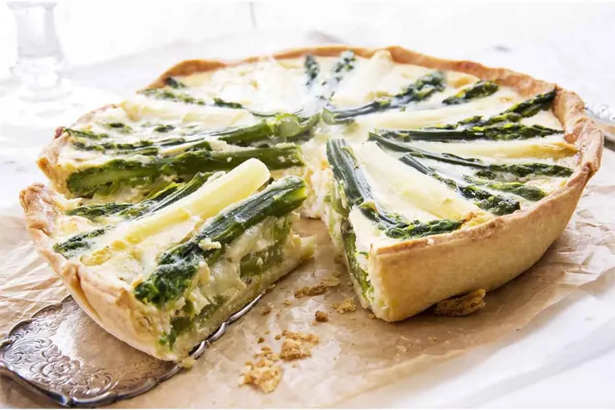 Spargelquiche mit grünen und weißen Stangen auf einem Tisch [Foto: AdobeStock_HLPhoto]