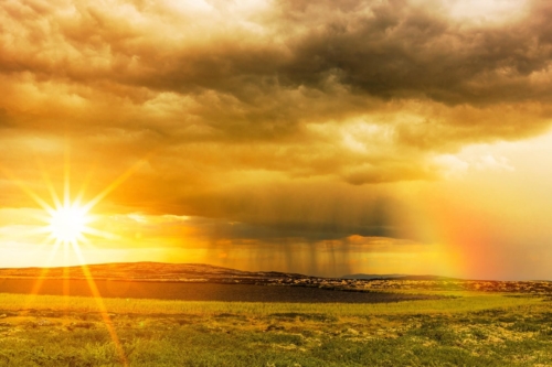 Die scheinende Sonne, eine Regenwolke mit Schauern und ein Regenbogen vor einem goldenen Himmel, auß0erdem ein See und Wiesen