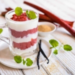 Dieses Joghurt-Rhabarber-Dessert ist ein Oster-Rezept fuer alle, die es leicht und sueß moegen. Hier in einem Glas angerichtet und auf einem Unterteller mit Vanilleschote serviert. [Foto: AdobeStock_noirchocolate]